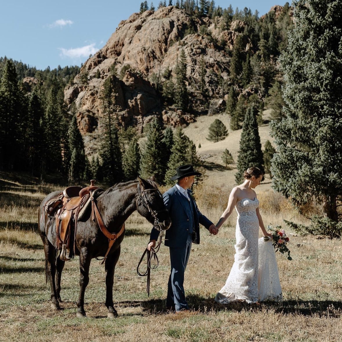 A groom and bride with a saddled horse below the rocks