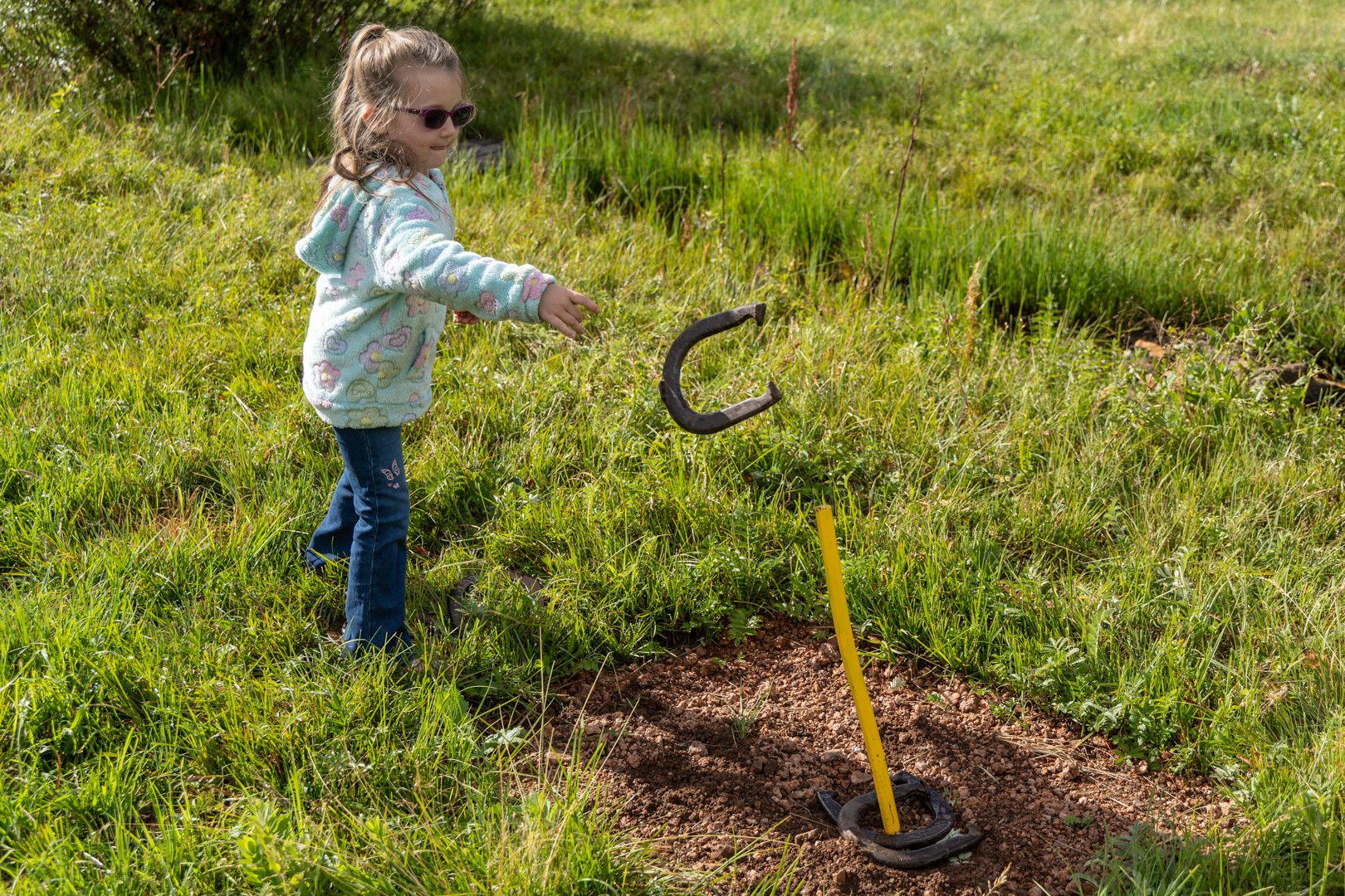 A young guest pitching horseshoes in the meadow