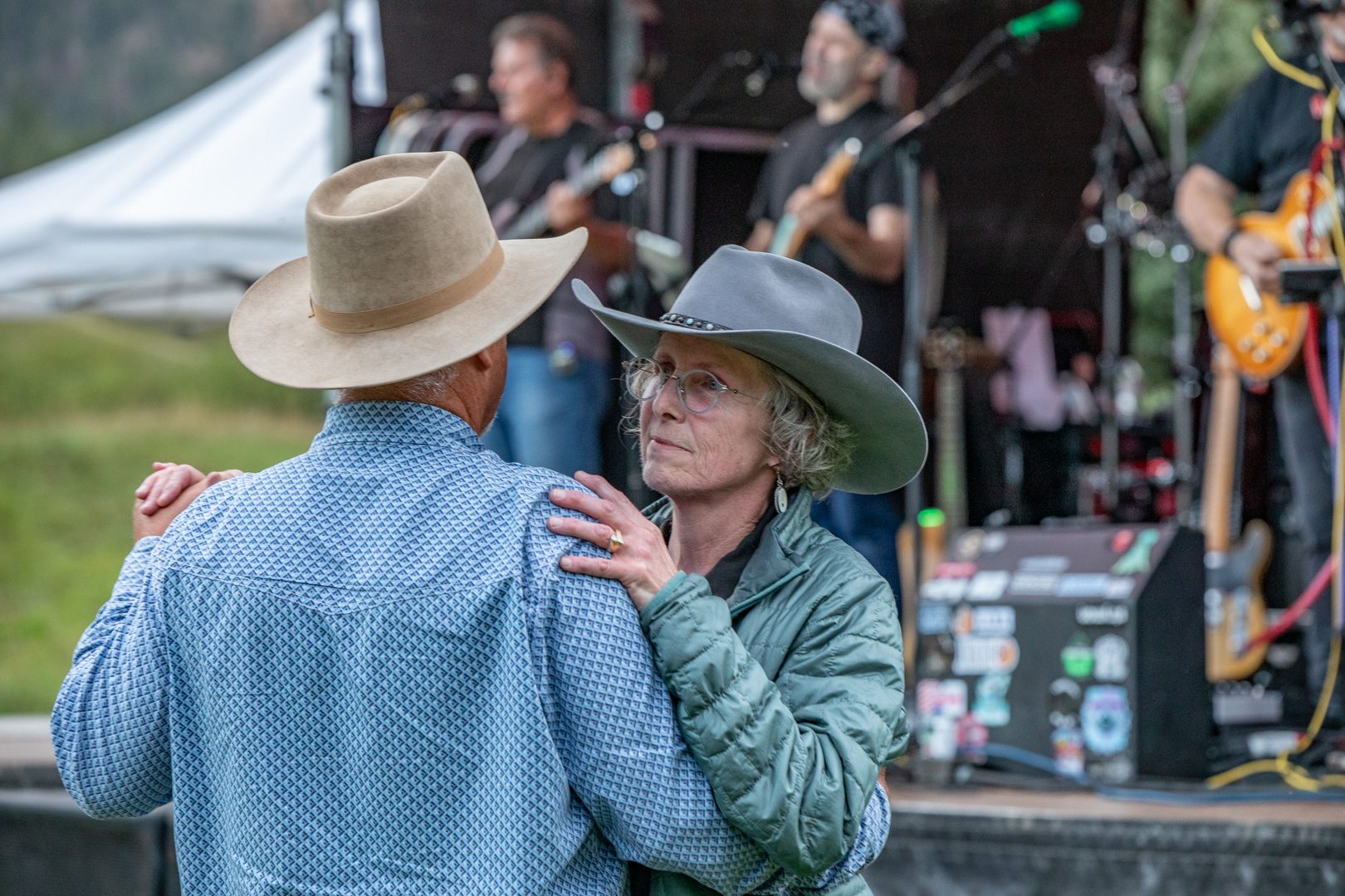 An older couple in cowboy hats slow dance by the stage while the band plays at an Elk Glade evening event